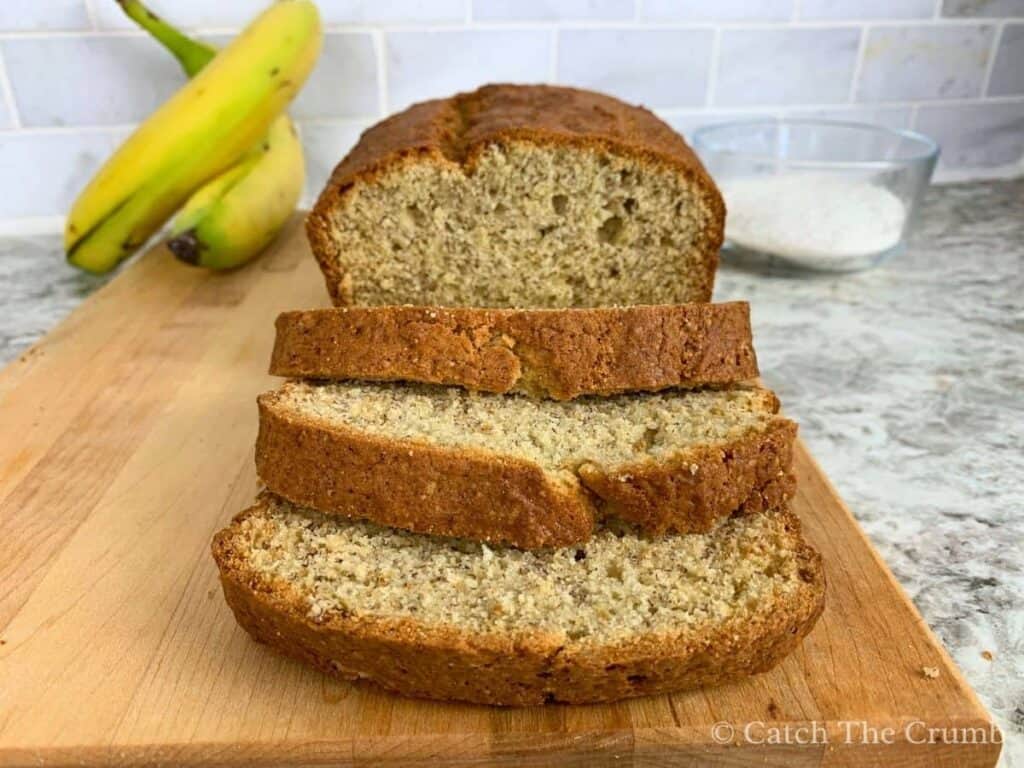loaf of banana bread cut in slices on a cutting board