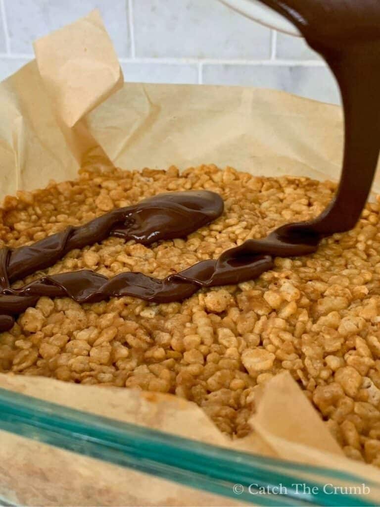 melted chocolate and peanut butter being spread over the base