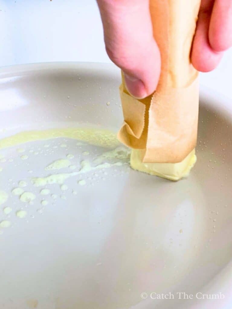 Rubbing the bottom of a pan with a stick of butter