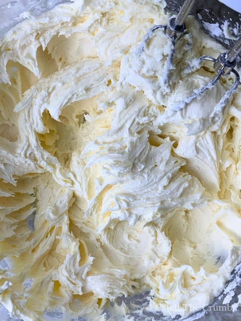 a mixing bowl with softened butter, 1 cup powdered sugar, vanilla, and salt being mixed together