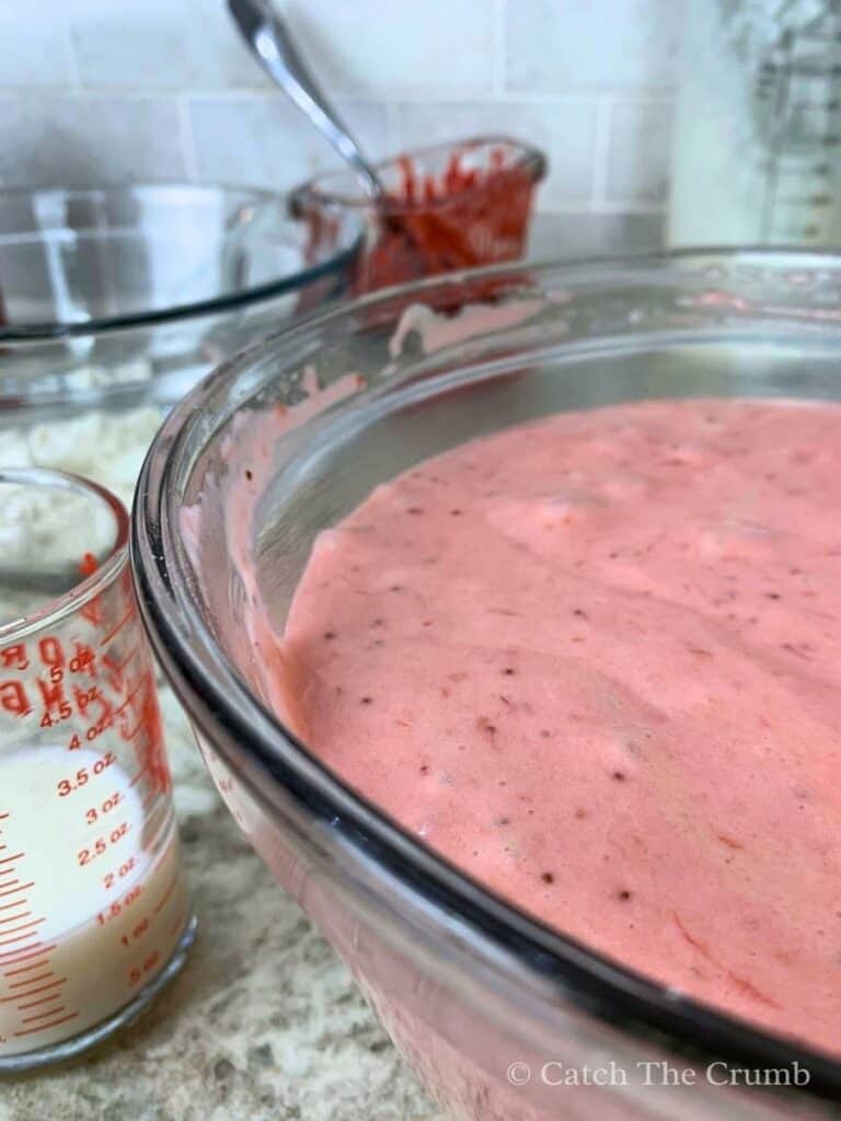 a mixing bowl with the mixture, milk, and strawberry reduction mixed in