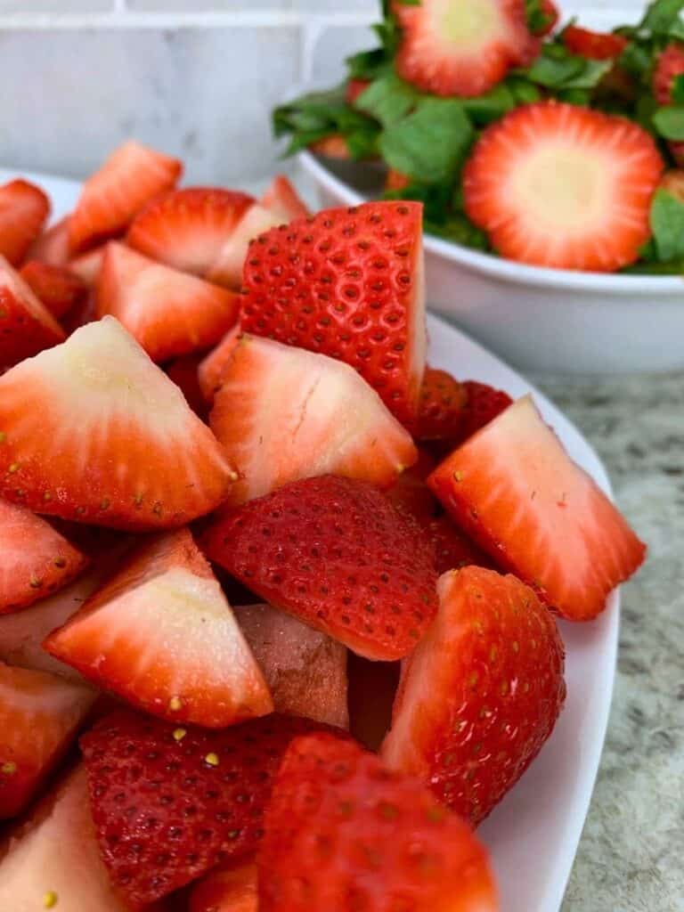 a plate of hulled and quartered strawberries