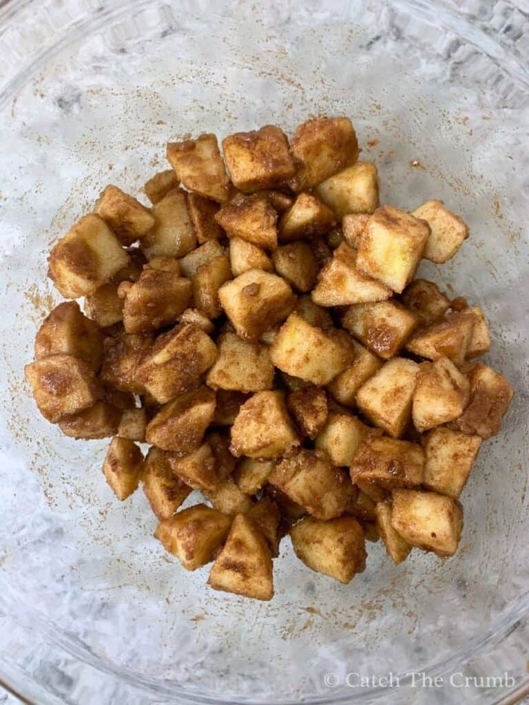 apples mixed with cinnamon and brown sugar in a mixing bowl