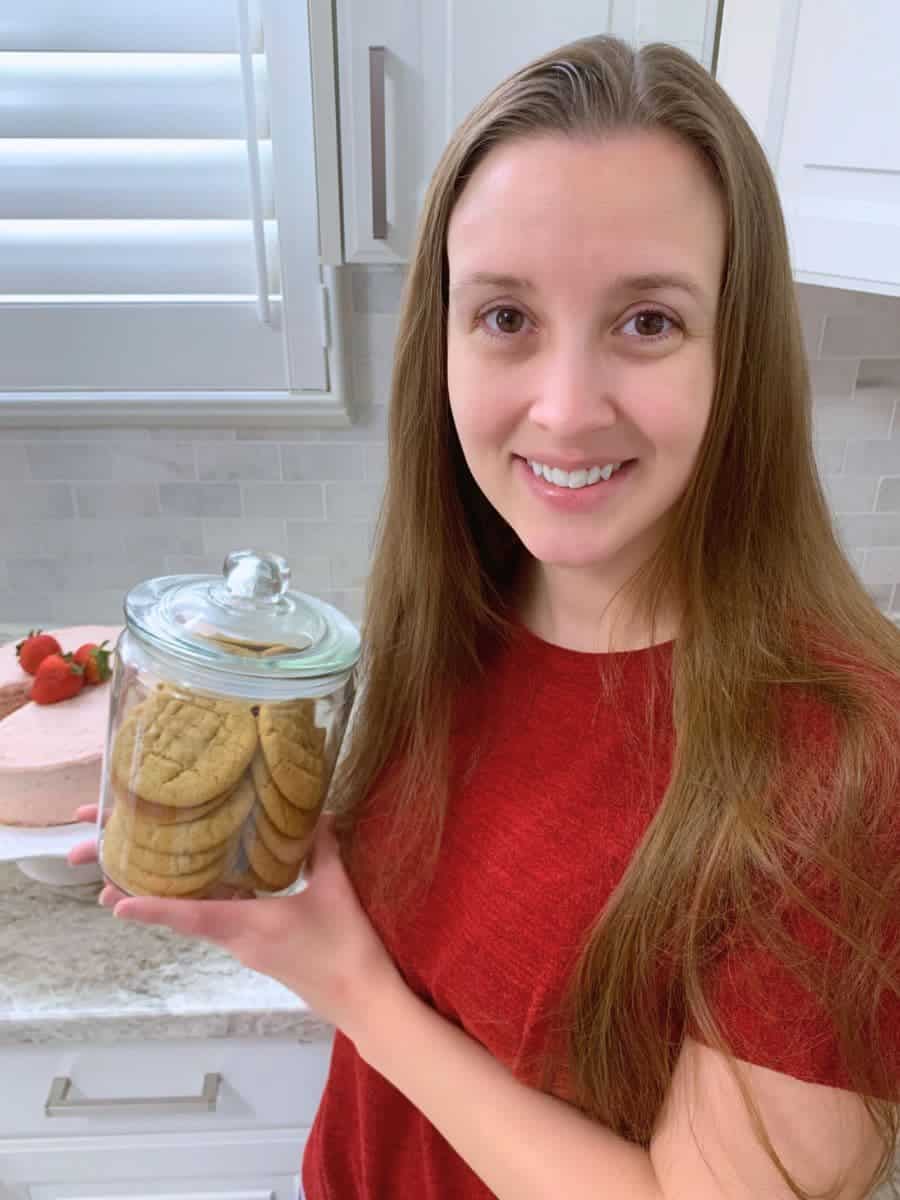 cassandra from catch the crumb holding a jar of peanut butter sourdough cookies