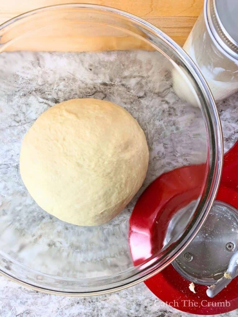 dough ball sitting in a mixing bowl after mixing
