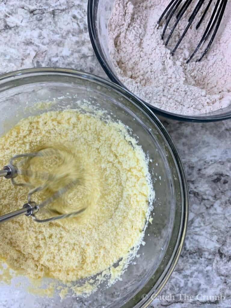 mixing bowl containing flour, baking powder, baking soda, cinnamon, and salt next to another bowl that is mixing butter, granulated sugar, eggs, vanilla, sourdough discard, and milk