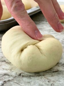 pinching the corners of a dough ball inward toward the center