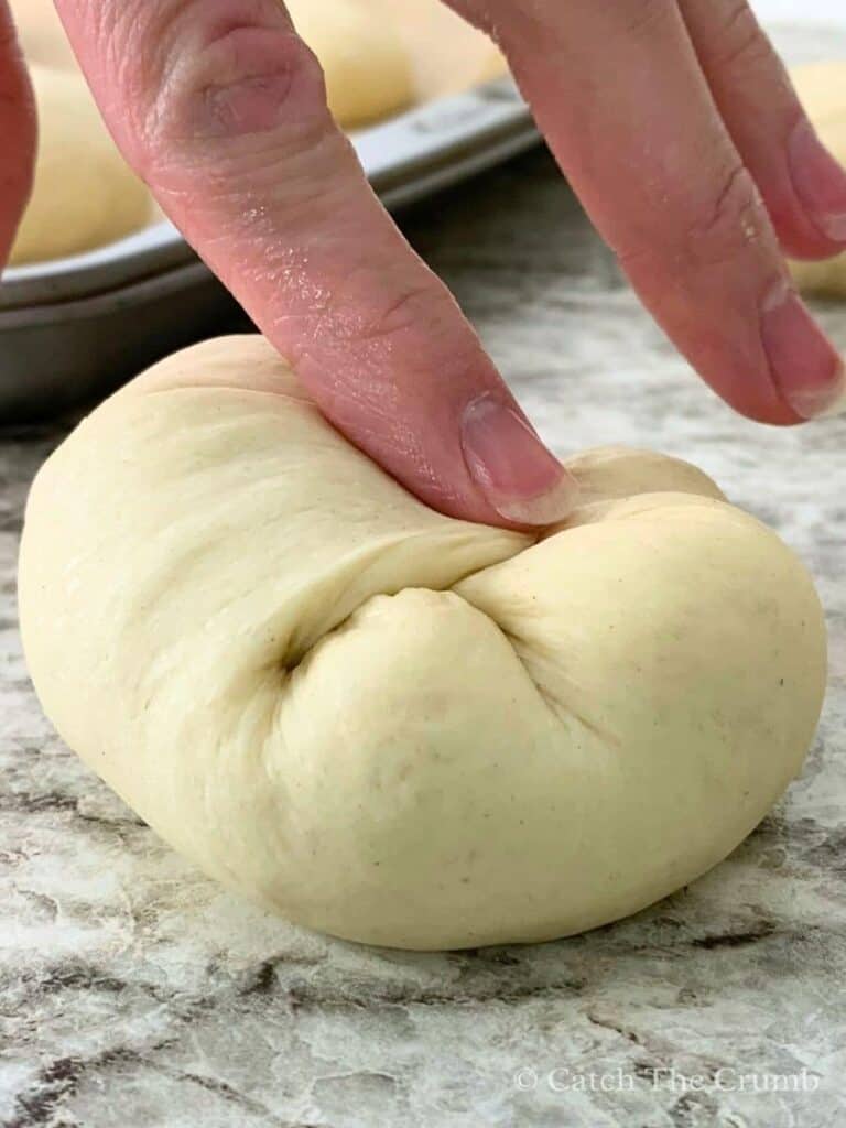 pinching the corners of a dough ball inward toward the center