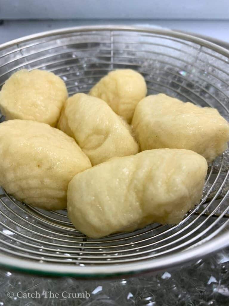 sourdough discard pretzel bites being removed from baking soda bath