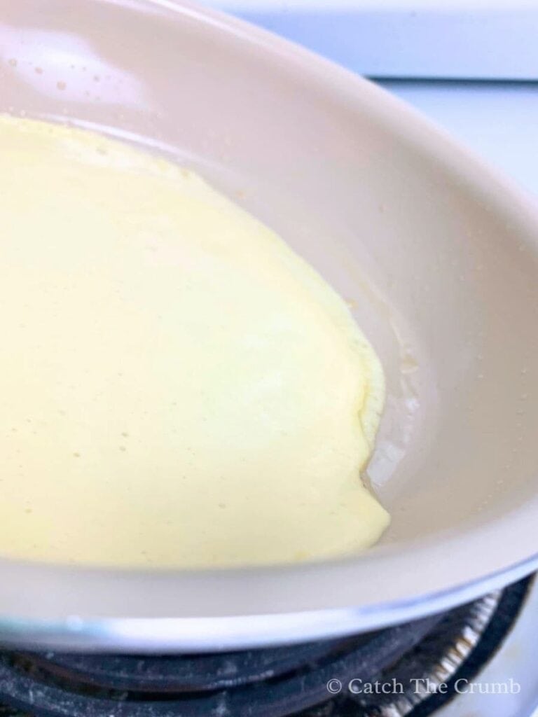 swirling sourdough crepe batter in a circular motion to spread it thin and evenly