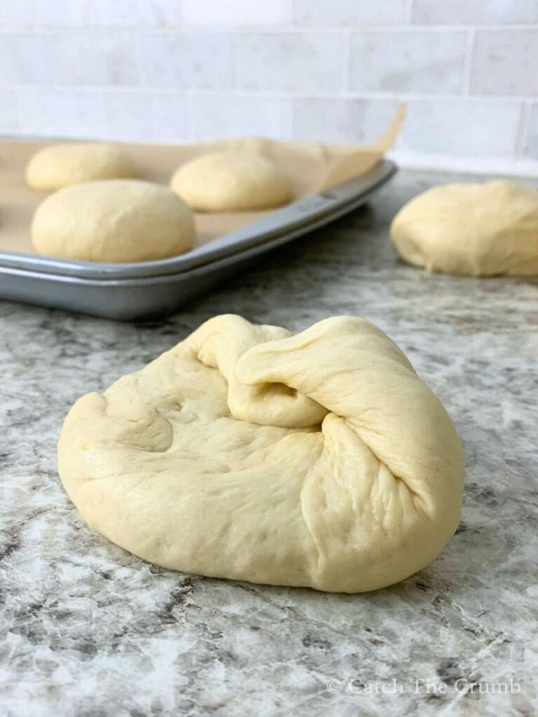 the corners of a flat dough ball folded inward toward the center