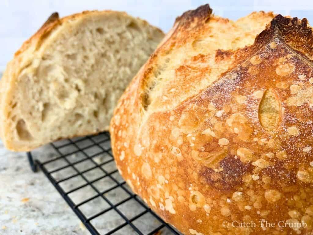 sourdough bread loaf cut in half sitting on a wire rack