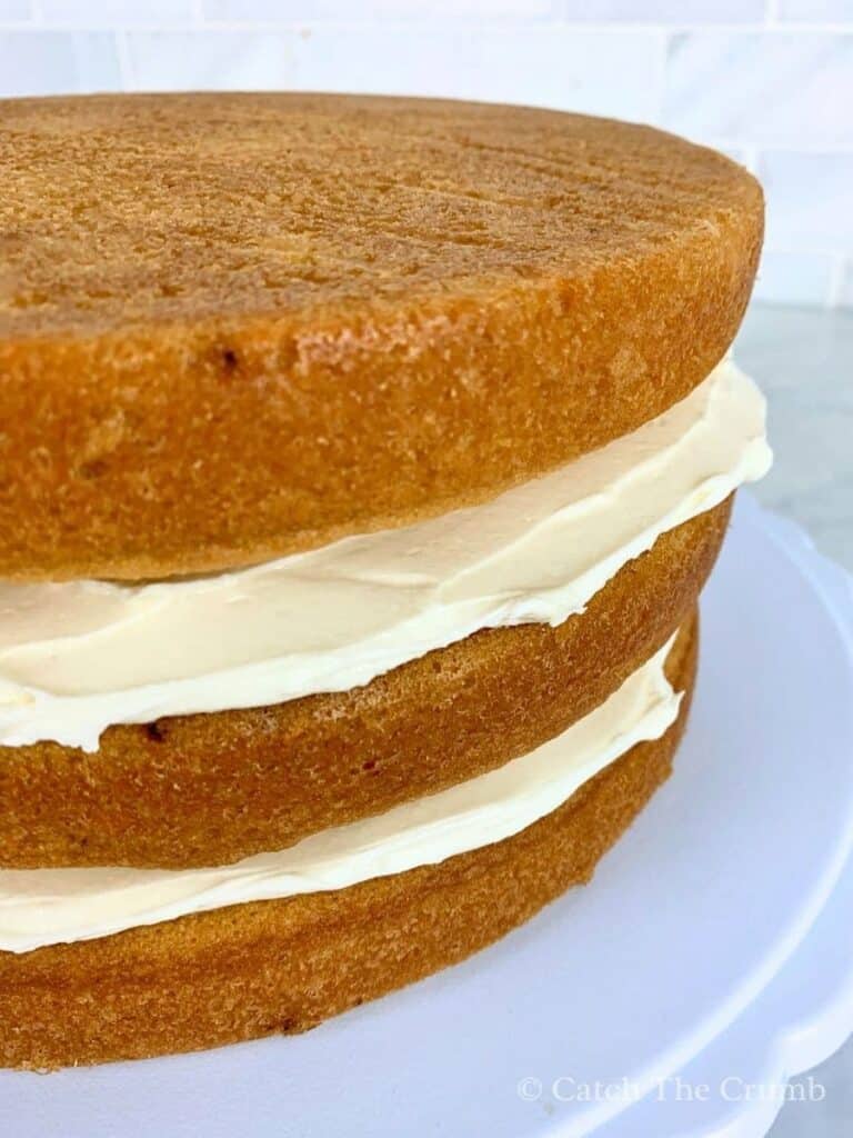 the top layer of the sourdough vanilla cake being added onto the other two layers