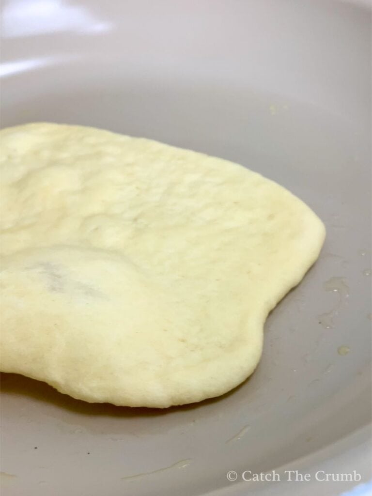 cooking naan in a frying pan over medium heat