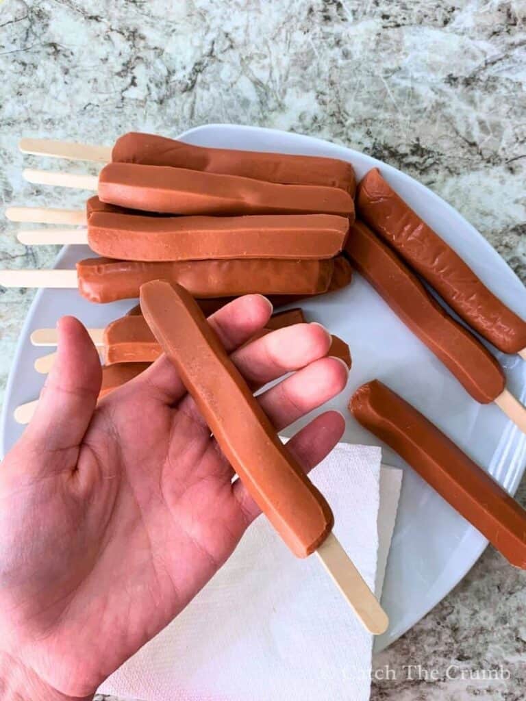 inserting popsicle sticks into the end of each hot dog