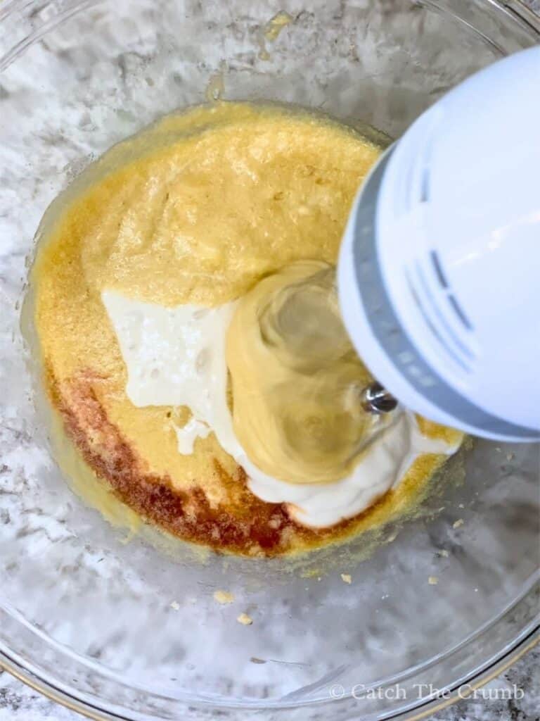 mixing eggs, vanilla, and sourdough discard in a mixing bowl with a hand mixer