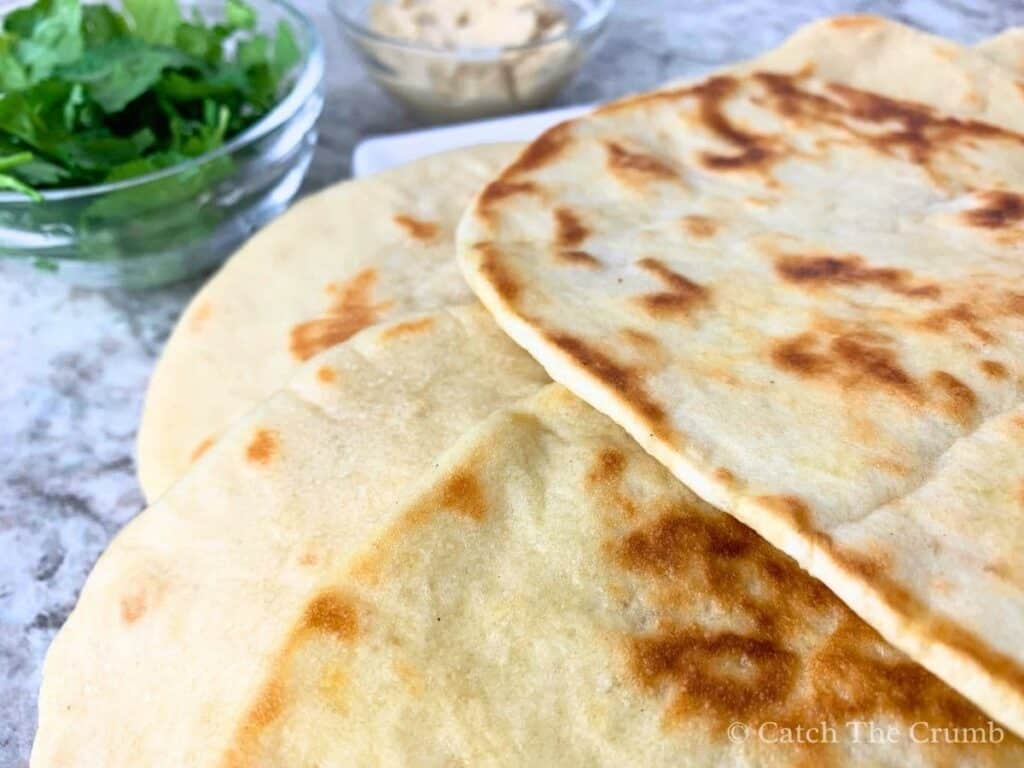 sourdough discard naan stacked on a plate