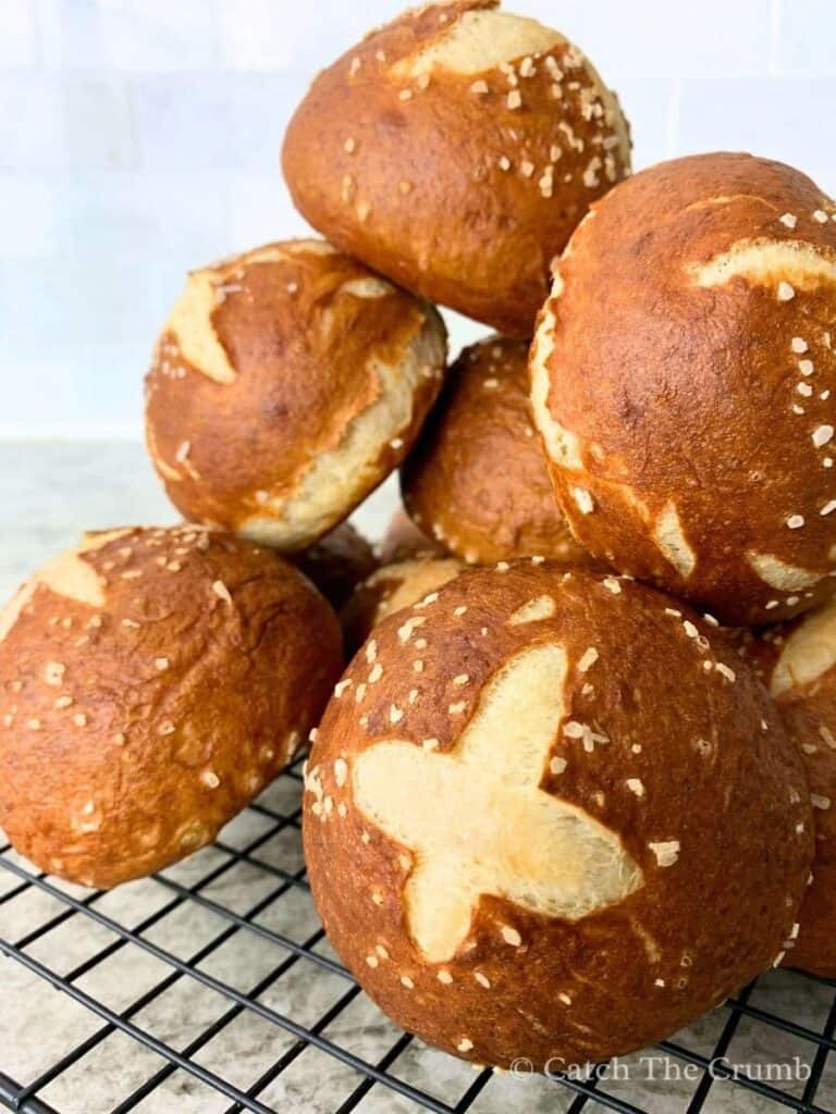 sourdough pretzel buns stacked on a wire rack
