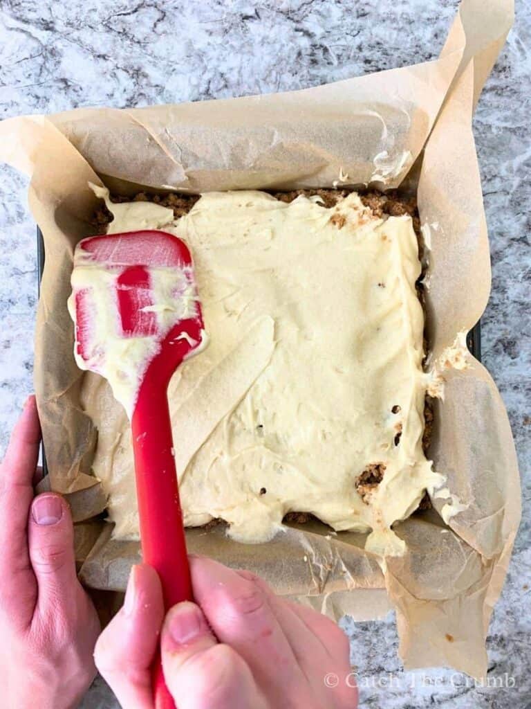 spreading a layer of batter on top of a layer of crumble